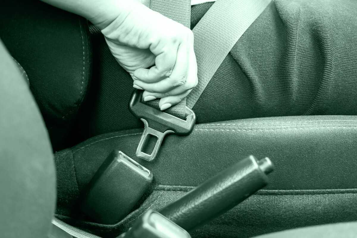 Close up of woman hand buckle the car safety belt.
