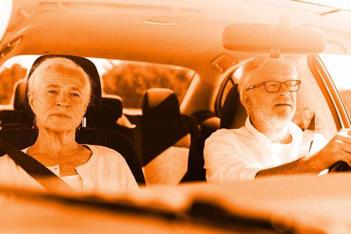 Elderly couple driving in a car with a warm, orange filter.