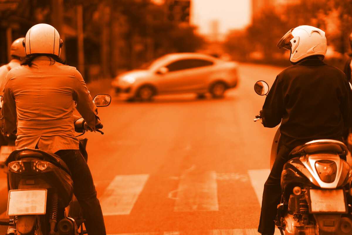 Two motorcyclists waiting at a crosswalk during sunset in Nevada.
