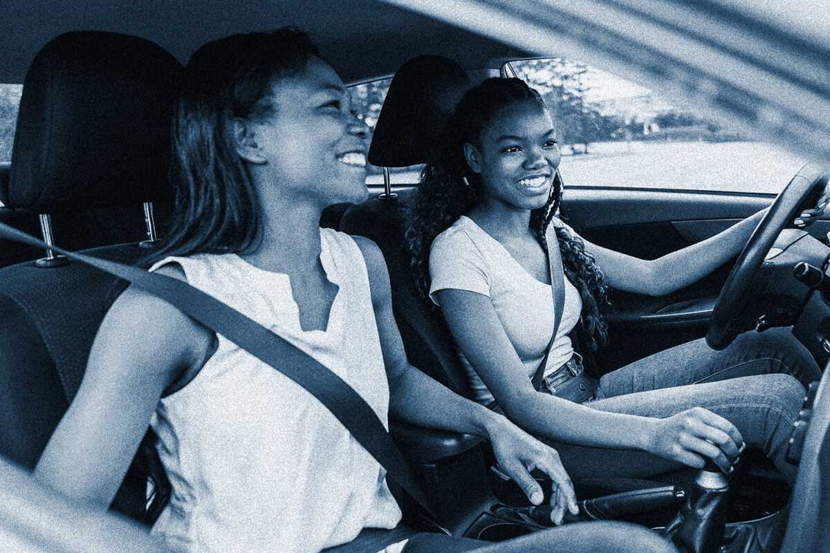 Two women smiling and enjoying a car ride together.